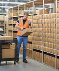 Worker using Two Shelf Foam Utility Cart With Lipped Shelves And Ergonomic Handle Black 500 Lb Capacity Durable Rolling Cart in warehouse