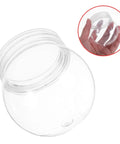 Close-up of a clear 4 inch snow globe kit with fillable plastic balls and screw cap, hand holding the globe for DIY decor and gift ideas.
