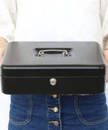 Person holding locking cash box with money tray and security cable, heavy duty metal safe for tips and cash, key lock visible
