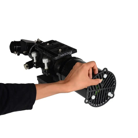 Hand adjusting a photography gear component with a black control setup against a white background.