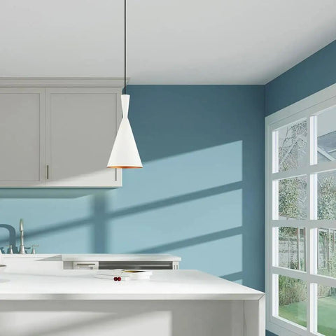 White 7.25-Inch Mini Pendant Light With Gold-Interior Metal Shade hanging in a modern kitchen, adjustable cord visible.