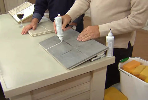 Person using Easy Clean Grout Finish Kit With Color And Seal Grout, Stain Resistant Finish With Protective Barrier, on tile surface.