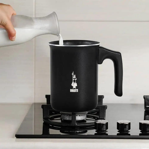 Tutto Crema Milk Frother Black Barista Grade, 1L Capacity on stovetop with milk being poured, not compatible with induction.