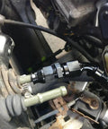 Two black aluminum 6AN female flare to 3/8 in tube OD compression fuel line fittings on a vehicle