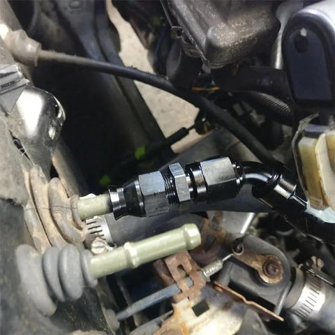 Two black aluminum 6AN female flare to 3/8 in tube OD compression fuel line fittings on a vehicle