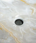 Close-up of the center drain in a Bathroom Sink Bathroom Sink Marble Ceramic Sink with elegant white and gold veining.