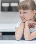 Child observing a glass of clear water on a kitchen counter, illustrating water purity.