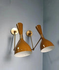 1950 Mid Century Italian Hardwire Brass Wall Sconce Pair Brown Wall Fixture Diabolo Lamp with golden shade against blue wall.