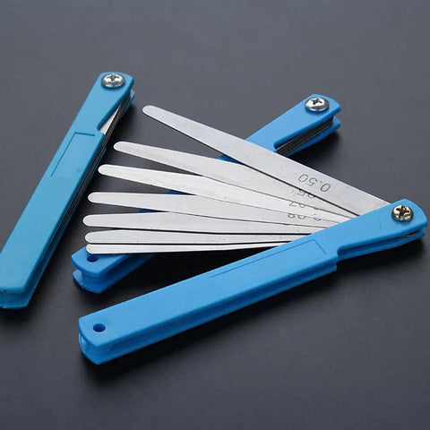 Top Shelf Feeler Gauge Set With Rock Solid Stainless Steel Blades For Nailing Dead Accurate Gap Measurements And Tappet Valve Adjustments On Every Hardcore Hobbyist Or Weekend Mechanic Garage Project, stainless steel blades with blue handles.