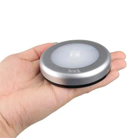 Hand holding 3 Pack Motion Sensor LED Night Lights Indoor Magnetic Stick On Battery Powered Under Cabinet Lighting