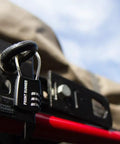 Small Stainless Steel Combination Cable Lock For Overland Truck Racks Custom Combo Code on a black mount with a red bar.