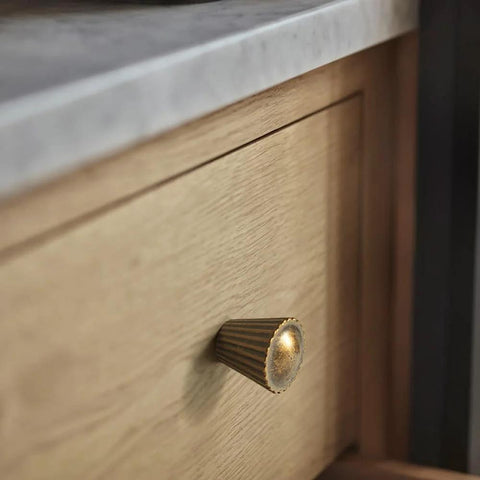 Six Pack Antique Brass Cabinet Knobs With Fluted Trumpet Ends installed on wood kitchen drawer