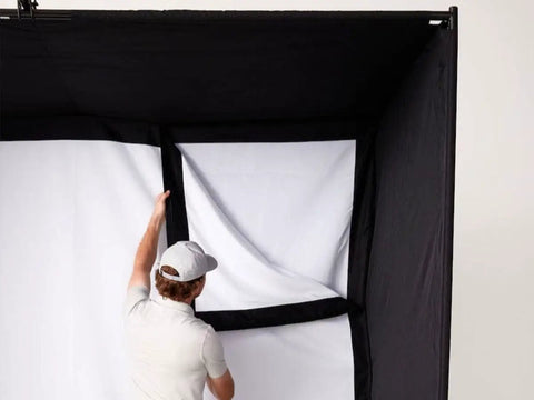 Person assembling enclosure of All In One Home Golf Sim Studio Bundle With Launch Monitor Enclosure Screen 5x5 Hitting Mat ZW350ST Projector