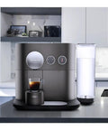 Prime Smart Espresso Machine Pulling Killer Shots On The Fly With Bluetooth App Sync Rotating Dial High Pressure Pump And Zero Hassle Daily Cleaning In Sleek Anthracite Grey with coffee cup.