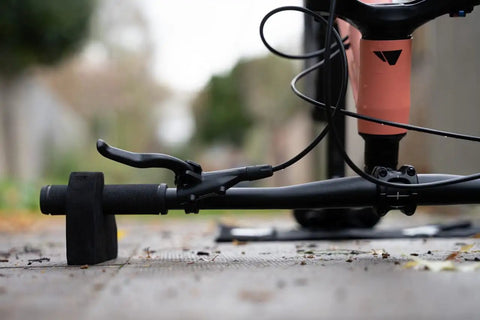 Close-up of Flipstand Compact Bike Stand with handlebar stabilizers, demonstrating its use for repairs on a bike, outdoor setting.