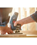 Person using Lightweight 12V Max EC Brushless Palm Edge Router Bare Tool for precise trim work on a wooden surface.