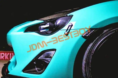 Close-up of car front with Orange Quick Release Fasteners Kit For Cars With 6061 T6 Aluminum Construction And Powder Coated Finish