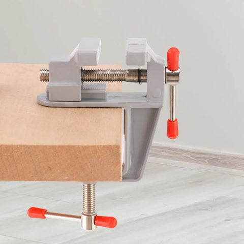 Reliable Mini Bench Vise With Quick Release Table Clamp And Drill Press Mount Holds Rock Solid For Jewelry Watch Fixing And Weekender Hobby Craft Projects Shop Staple, mounted on a wood surface.