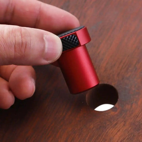 Close-up of red anodized aluminum Bench Dogs Clamp For Workbench Positioning And Planing Plug with non-slip pads in hand