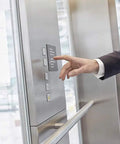 Person pressing elevator button inside modern building.