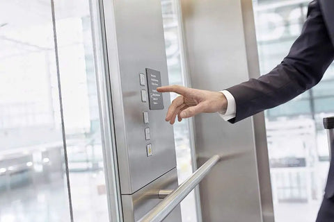 Person pressing elevator button inside modern building.