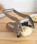 Front view of stainless steel French fry cutter with two blades and non-slip suction cups.