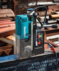 Makita HB350 1-3/8-inch magnetic drill on steel beam; teal housing with cord visible.