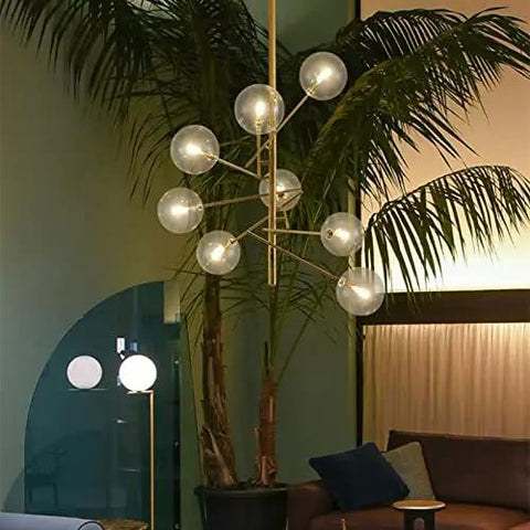 Modern Six Head Glass Pendant Ceiling Light With Warm White Bubble Shades And Brushed Chrome Frame, suspended over lush plants.