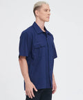 Men's Short Sleeve Work Shirt In Navy Blue Cotton Poly Blend Durable Button Front Uniform Features Double Chest Pockets Built Hella Tough For The Daily Grind And Extra Large Cut on a model from the side angle.