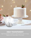 DIY Snow Globe Kit With Ten Clear Plastic Water Globes And Screw Off Caps by a white cake on a table setting