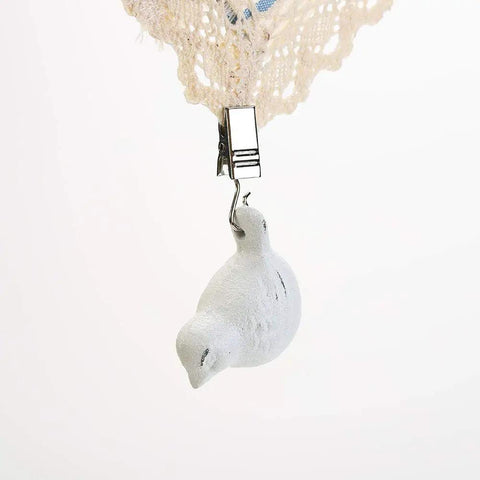 Cast Iron Tablecloth Weights 4 Pack With White Bird Pendant Clips Heavy Duty Tablecloth Clamps For Home Garden Parties Weddings Camping And Picnics Keeps Your Linen Flat And Secure, showing a close-up of a white bird-shaped cast iron weight clipped to lace tablecloth.