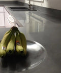 Pro Grade Water Based Concrete Countertop Sealer Kit Food Safe Formula delivers a crisp semi gloss finish on polished gray countertop with bananas.