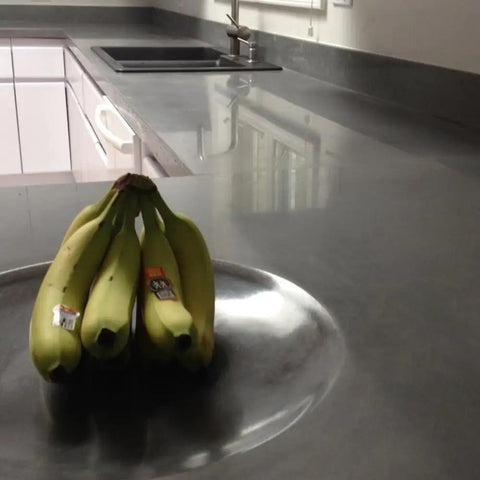 Pro Grade Water Based Concrete Countertop Sealer Kit Food Safe Formula delivers a crisp semi gloss finish on polished gray countertop with bananas.