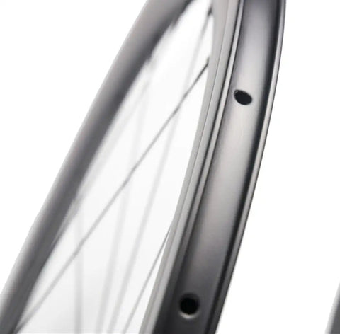 Close-up of Pro Grade 700C Carbon Clincher Front Wheel showcasing rim holes and full carbon fiber material.