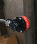 Side view of Amazon 600A magnetic welding ground clamp installed on a steel pipe with a red label.
