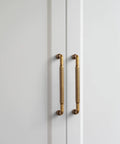 Antique Brass Cabinet Pull Handles Six Pack 5 Inch Vintage Vertical Grooved Textured Grip on white cupboard doors.