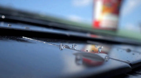 Close-up of Heavy Duty Tough As Nails Clear Roof Sealer Stops Leaks Cold with water droplets on metal surface.