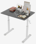 Game Changer Manual Crank Height Adjustable Standing Desk 32X24 Inch with books and stationery on a gray surface.