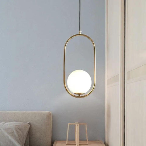 BEQAOR Modern Globe Pendant Light, 1-Light Oval Hoop Hanging Ceiling Fixture with Frosted White Glass Shade and Gold Finish Frame for Bedroom Bedside, hung over a bedside table.