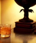 Lab Beaker Rocks Glasses Set Of 2 For Cocktails And Science Themed Barware With A Dope Scientific Twist on a table with books and lamp.