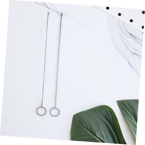 Two long needles from Five Piece Long Sewing Needle Threader Kit With Stainless Steel Hook Latch on marble with green leaves
