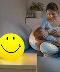 Smiley Face Night Light For Kids USB Rechargeable Portable Nursery Lamp with warm glow next to mom holding baby at night
