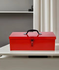 Slick Red Metal Toolbox Chest With Reinforced Carry Handle For Portable Gear Storage And Heavy Duty Tool Organization on a white table.