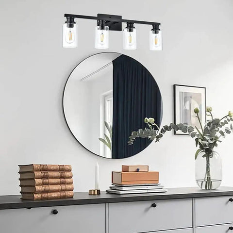 Industrial Indoor Four Light Bathroom Vanity Light In Black With Clear Glass Shades above a round mirror on white wall