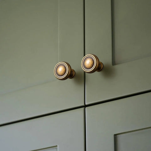Close-up of 6 Pack Antique Brass Zinc Alloy Cabinet Knobs And Drawer Pulls For Kitchen Cabinets on olive green doors.