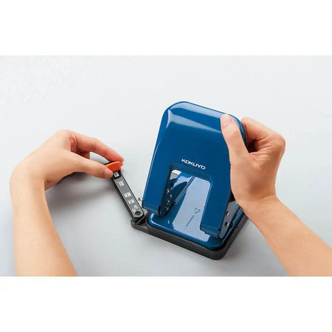 Person adjusting paper guides on Heavy-Duty 2-Hole Punch With Smooth Action, Handles Up To 37 Sheets, blue ergonomic design, top view