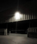 Dusk to Dawn LED Security Light 18W illuminating a dark garage exterior, showcasing the brightness of the adjustable two-head wall mount.