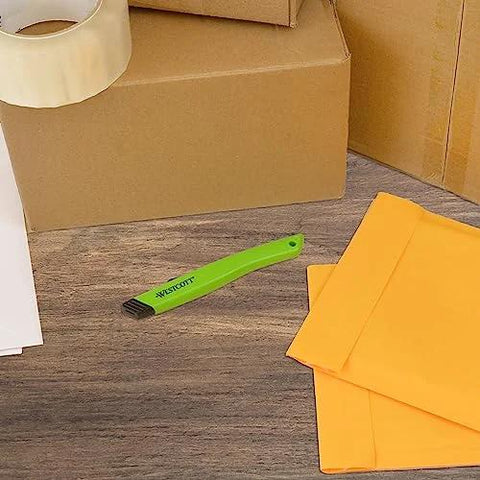 Front view of green Westcott ceramic box cutter with safety blade on a desk near yellow envelopes.