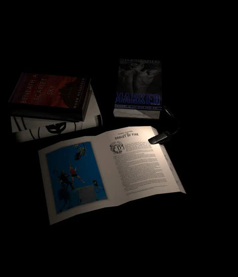 Grab And Go Clip On Book Light With 12 LED USB Rechargeable Battery illuminating open book on desk with other books