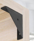Set Of Four Heavy Duty Corner Brace Brackets With Screws For Reinforcing Furniture Cabinets Bookshelves And Tables Right Angle Shelf Supports, black steel corner bracket close-up on wood.